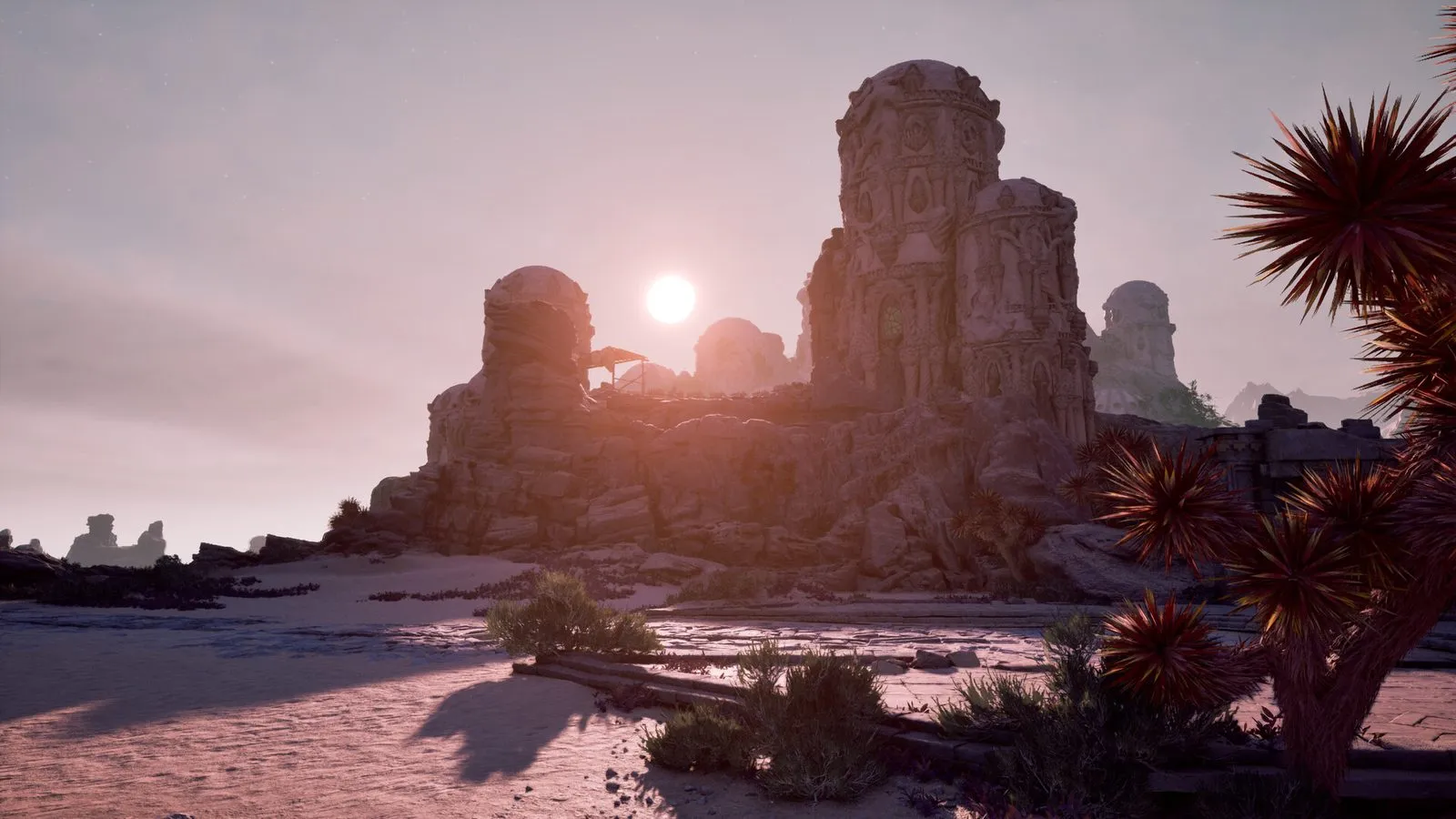 Un atardecer sobre ruinas de piedra tallada con cúpulas, en un desierto con plantas espinosas rojas