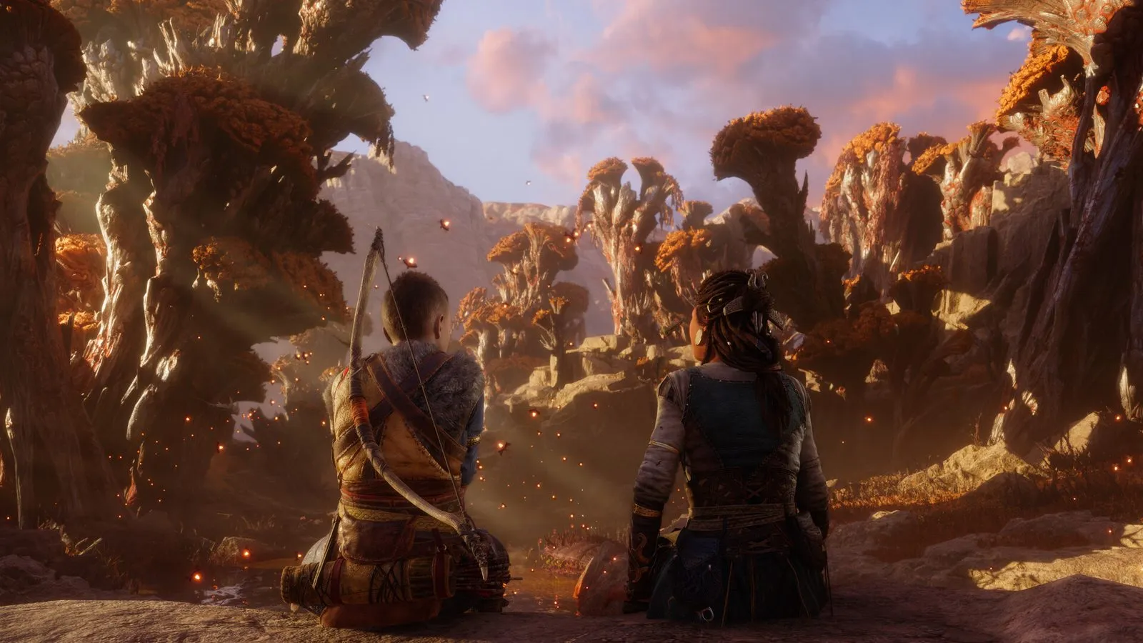 Atreus con el arco a la espalda y una mujer de trenzas sentados de espaldas, mirando un paisaje rocoso de árboles anaranjados al atardecer