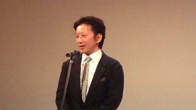 Hirohiko Araki, autor de JoJo's Bizarre Adventure, habla ante un micrófono en un acto en 2013, con traje oscuro y corbata clara
