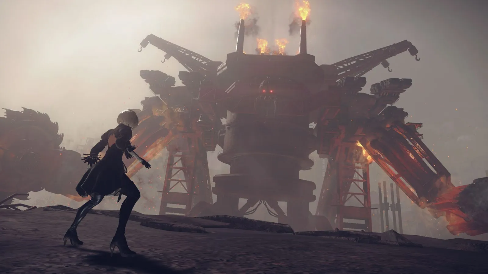 Una androide de vestido oscuro frente a una máquina gigante con chimeneas encendidas en un páramo de NieR:Automata