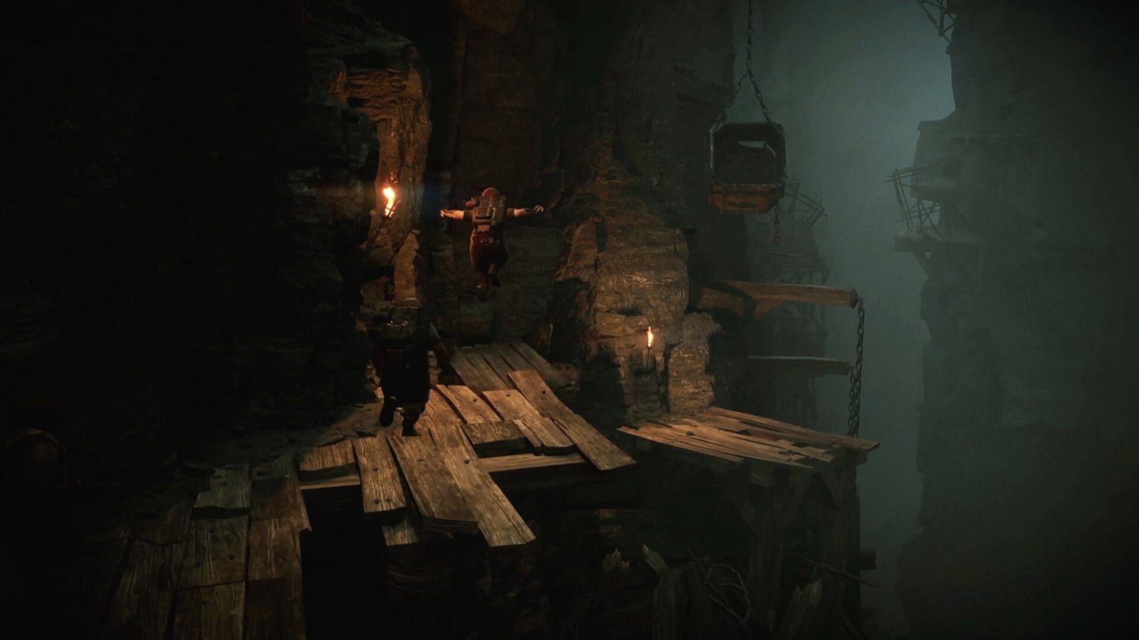 Dos enanos avanzan por una pasarela de madera pegada a la pared de un abismo oscuro, con una jaula colgada de cadenas