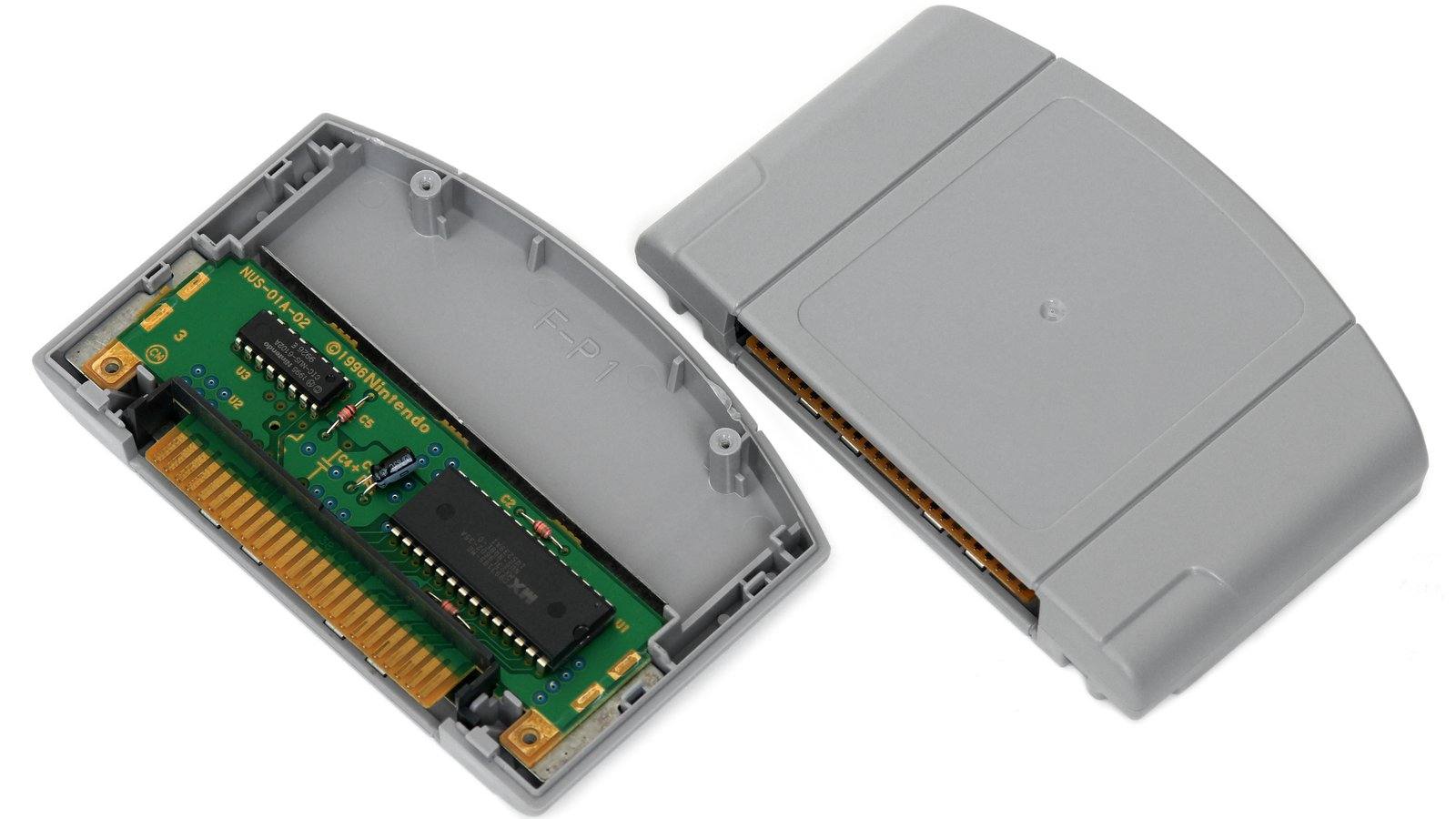 Cartucho gris de Nintendo 64, abierto a la izquierda con la placa verde a la vista y cerrado a la derecha, sobre fondo blanco y sin etiqueta de ningún juego