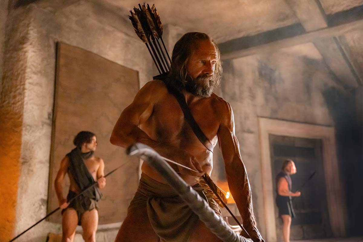 Un Ralph Fiennes sin camisa tensando un arco en El regreso