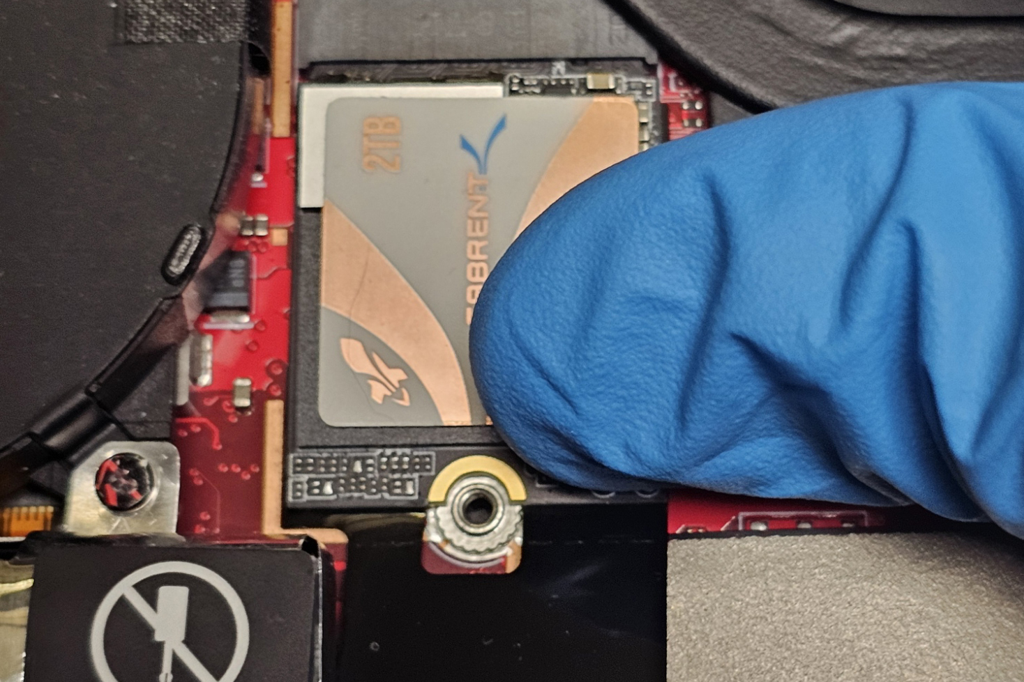 Una foto de un pulgar que fija un SSD M.2 en el zócalo M.2 del ROG Ally
