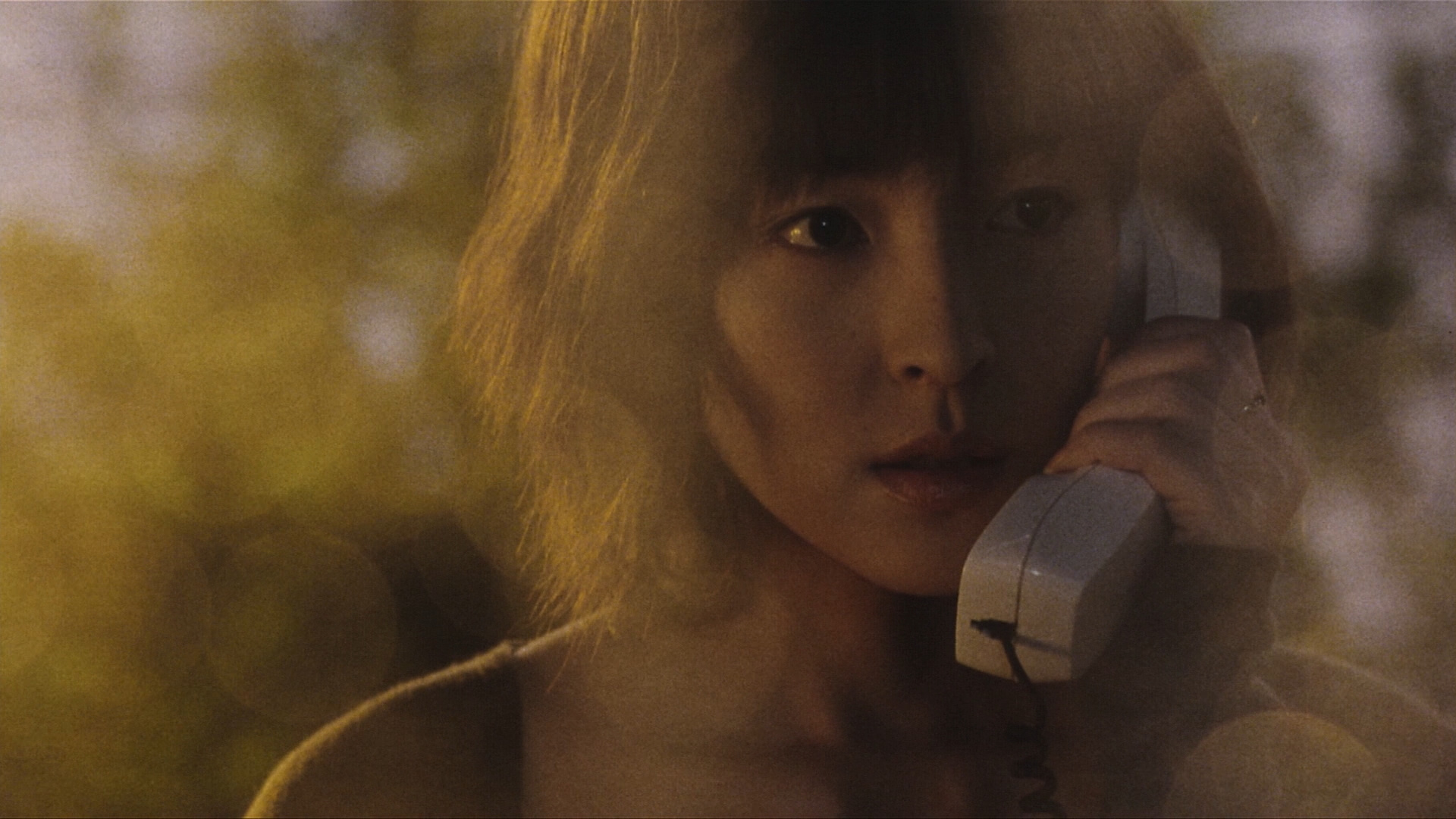 Kumiko asō como Michi Kudo sosteniendo un receptor telefónico con cable en su oído en Pulse.