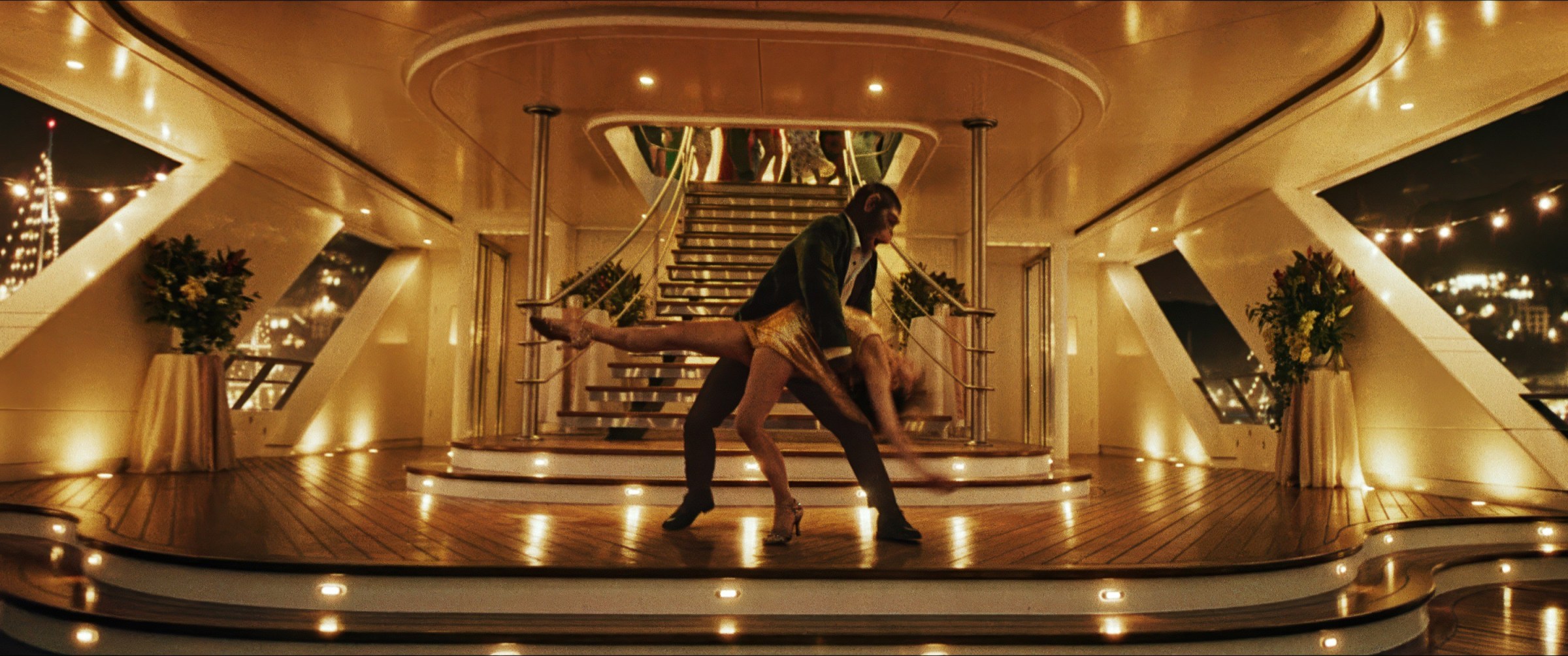 La estrella del pop Robbie Williams (como un chimpancé) baña a la estrella del pop Nicole Appleton (Raechelle Banno) durante un pas de deux en la cubierta de un yate privado en Better Man.